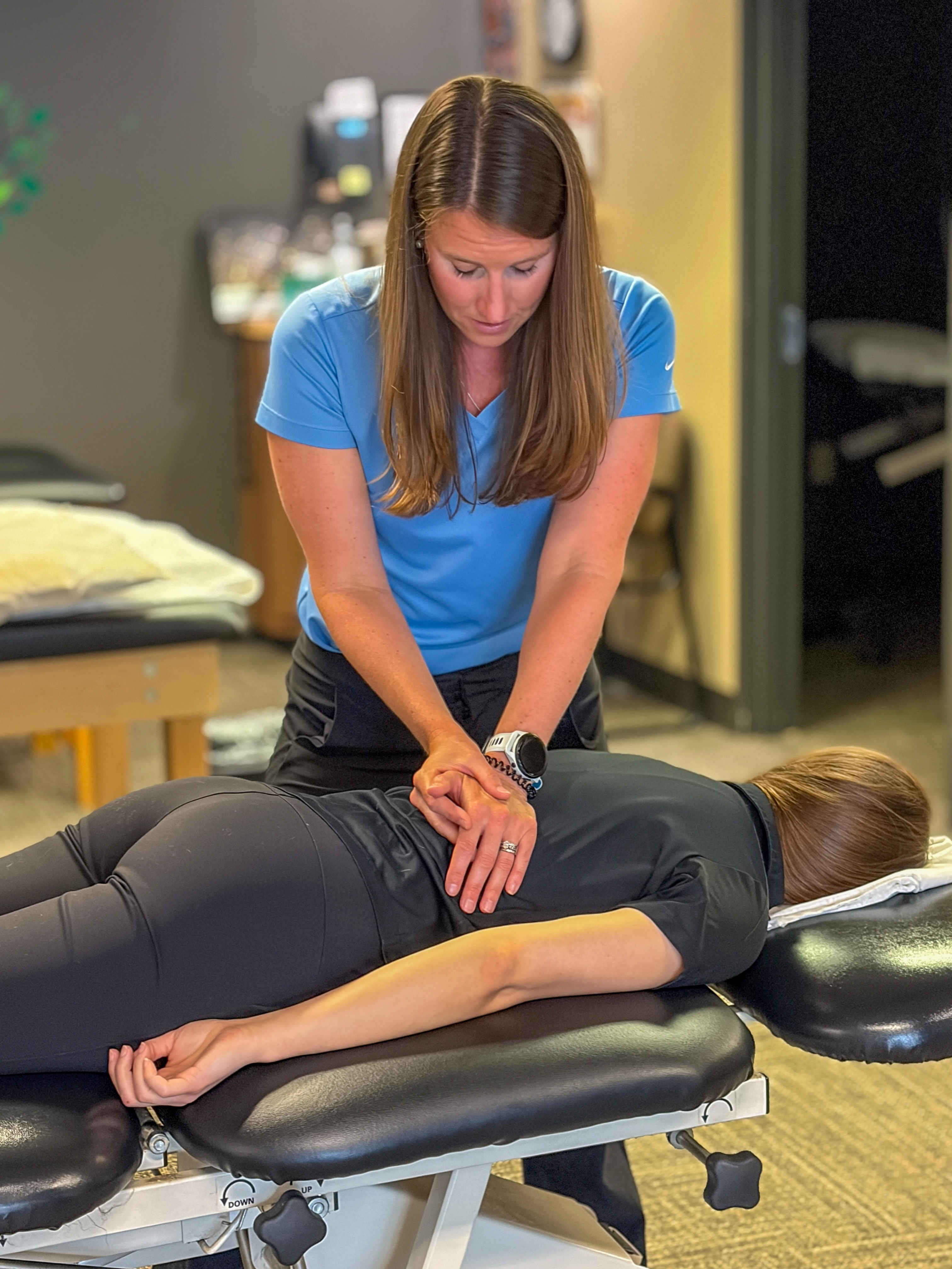 Physical therapist performing hands-on manual therapy on an athlete lying on a treatment table.