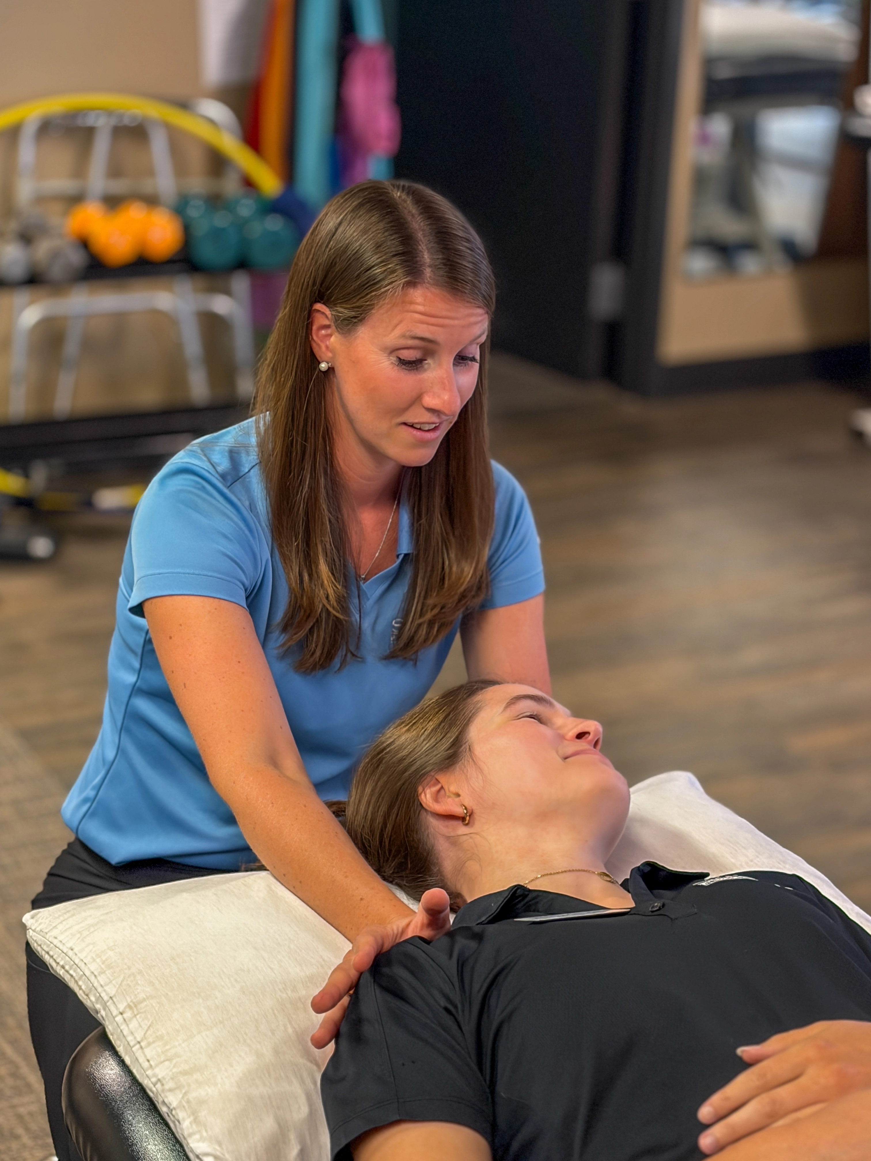 Physical therapist performing manual therapy on an athlete lying face down on a treatment table.